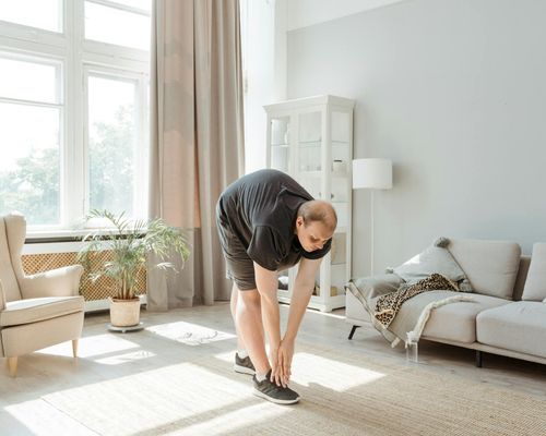 Person performing a stretching exercise in a bright room.